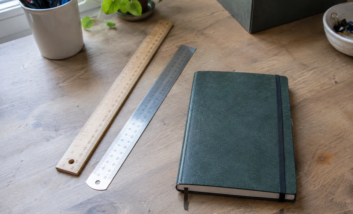 Deux règles et un carnet fermé sont disposés sur un bureau.