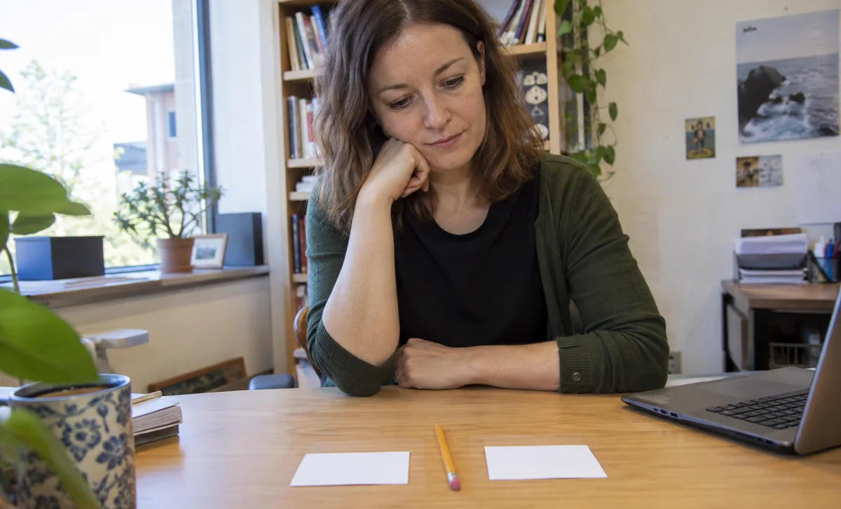Une femme regarde deux cartes vierges sur un bureau.