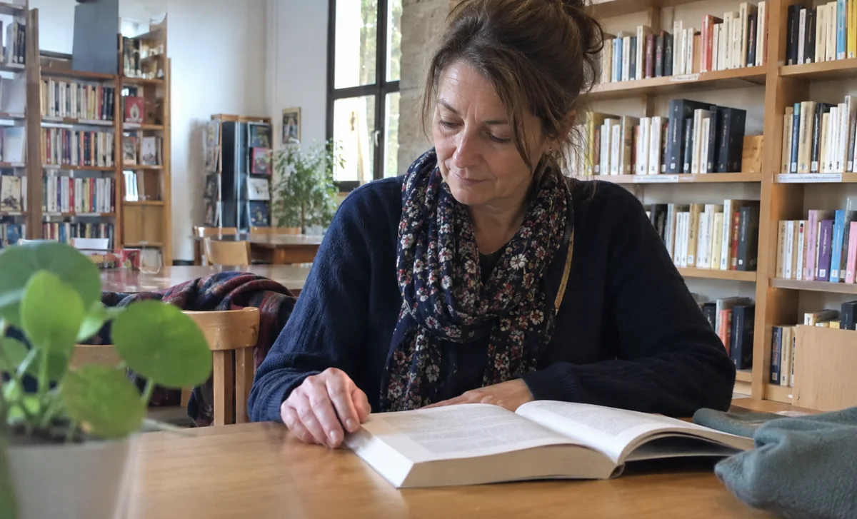 Une femme consulte un livre dans une bibliothèque.